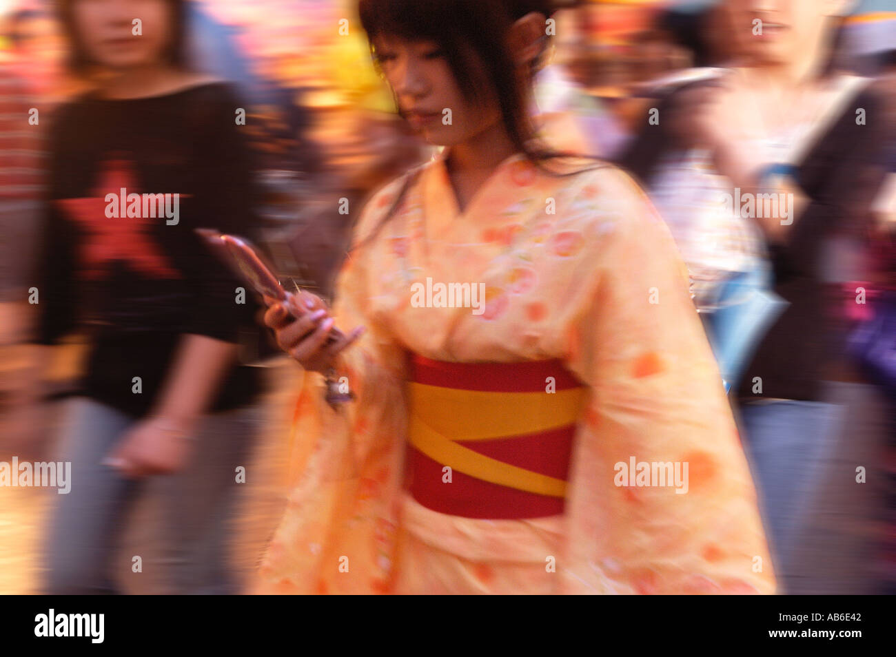 A lady in kimono using her mobile phone at night in Shinjuku entertainment district of Tokyo Japan Stock Photo