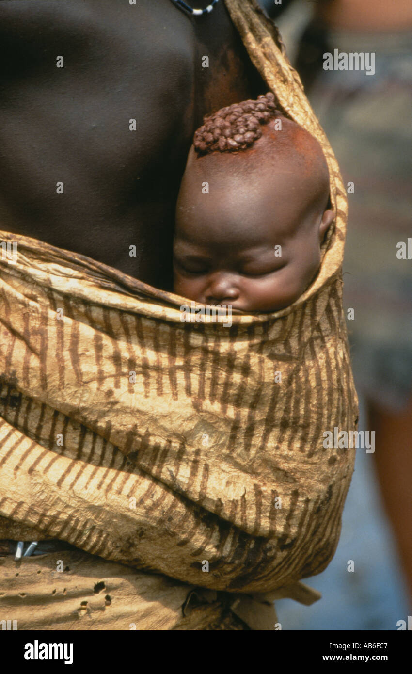 Mother carrying her baby on her back in a sling ,a member of the Bodi tribe along the Omo River ,Ethiopia Stock Photo