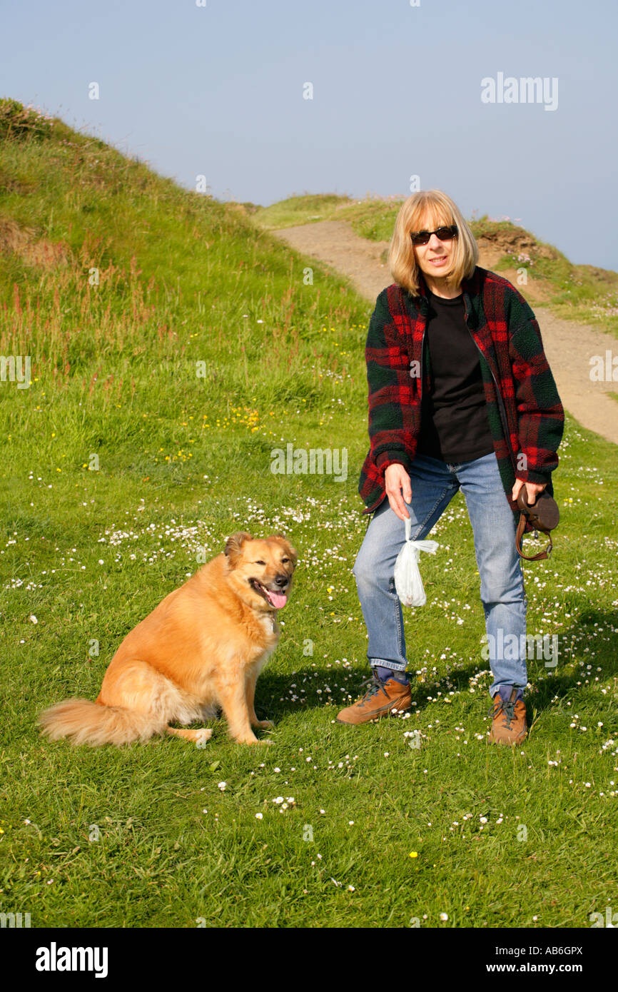 Dog and owner with bagged dog excrement in parkland. Stock Photo