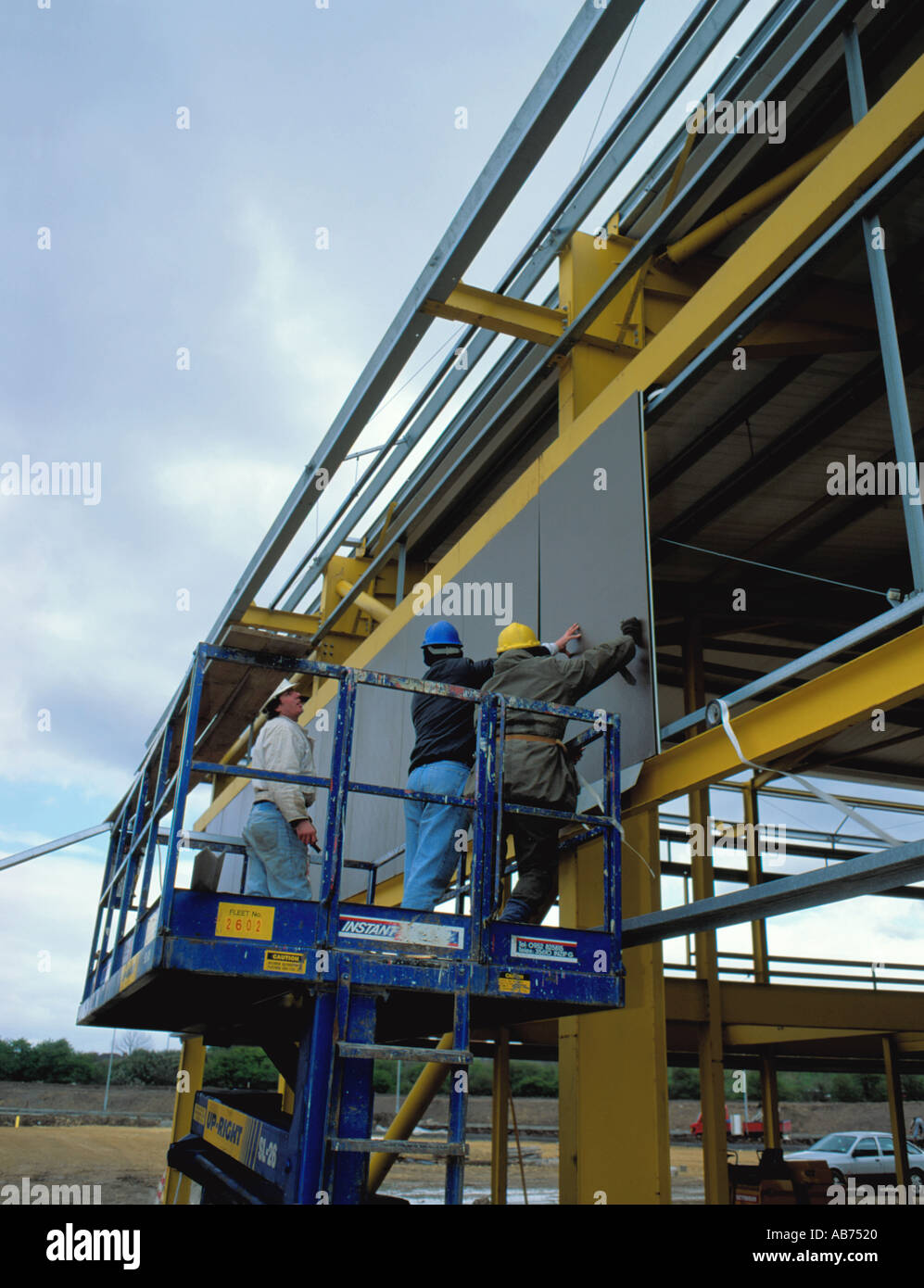 Workmen installing a cladding panel from a mobile hydraulic platform