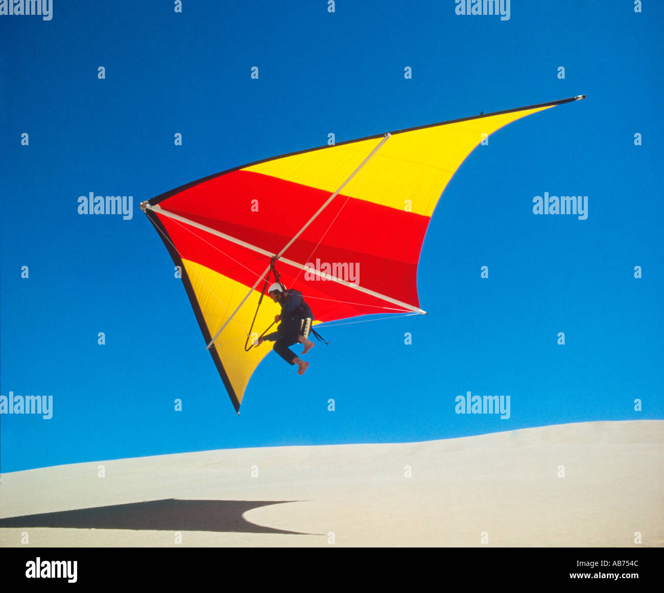 man taking off from sand dunes on a hang glider Stock Photo