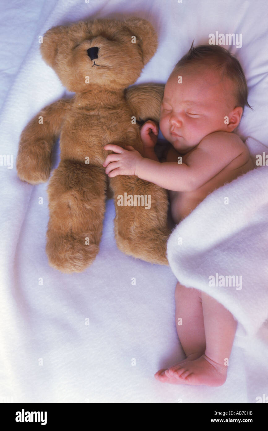 Baby sleeping with favorite teddy bear Stock Photo