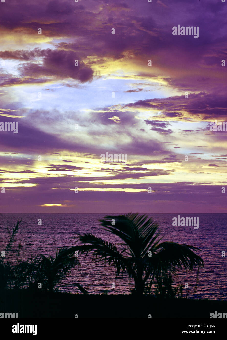 Purple skies across the ocean during a sunset on a tropical island Stock Photo