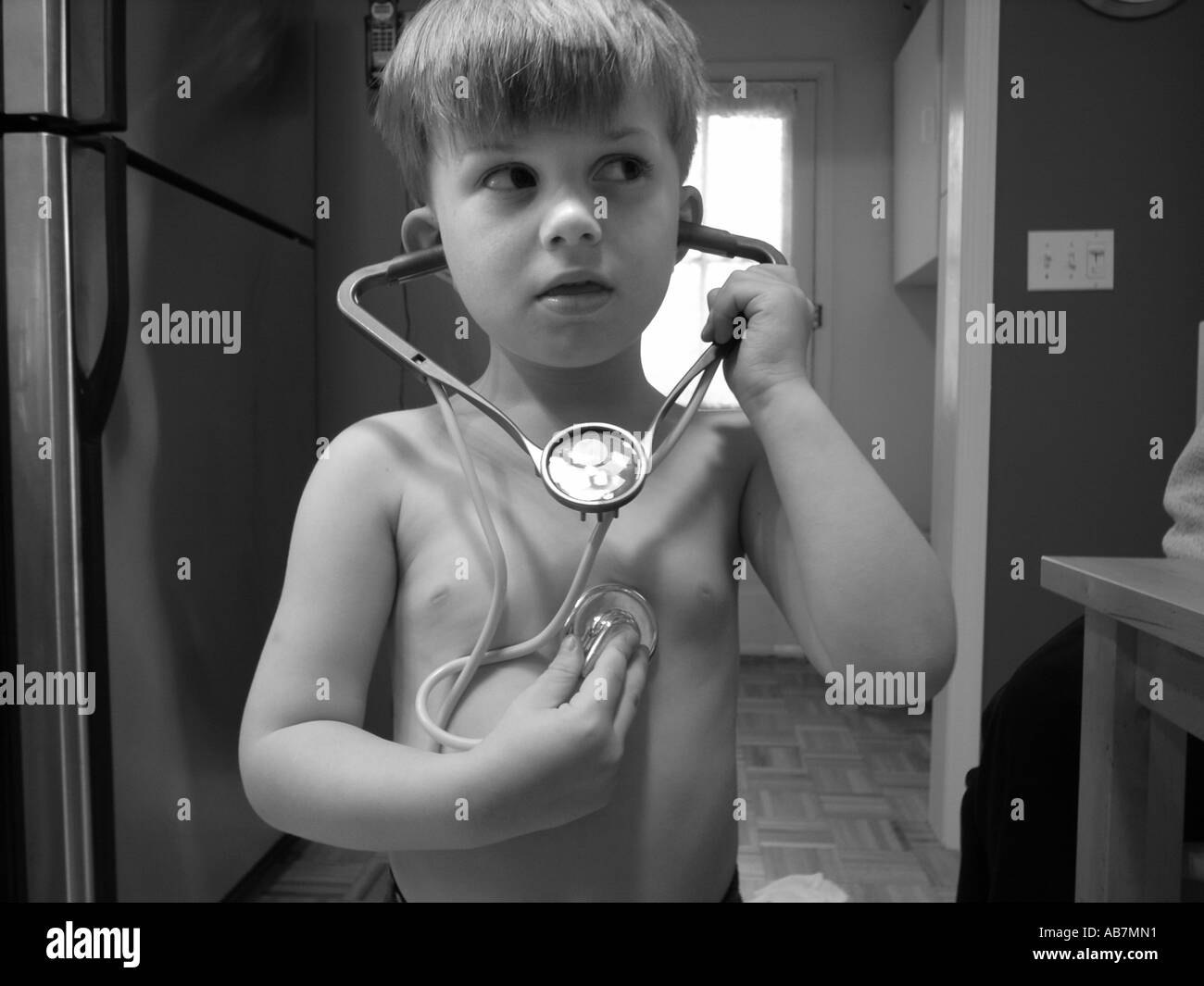 Photo of a Small Child playing with a toy Stethoscope listening to his own heart beat Stock Photo