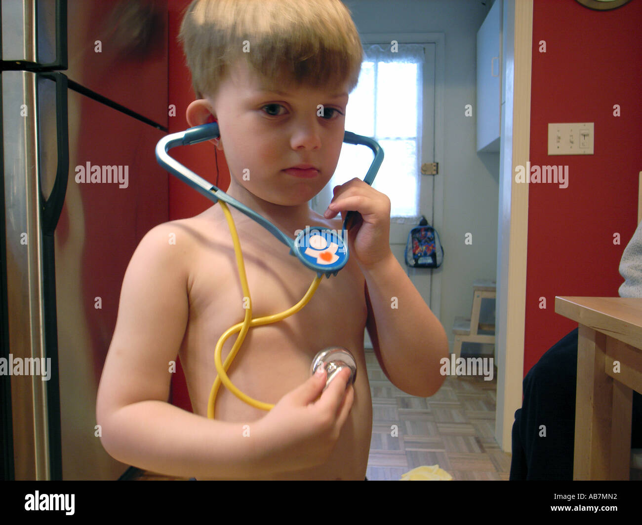 Photo of a Small Child playing with a toy Stethoscope listening to his own heart beat Stock Photo