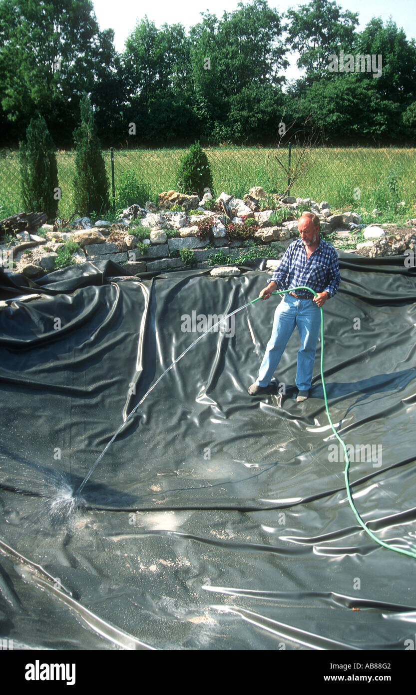 Man starts to fill up water in the pond hires stock photography and