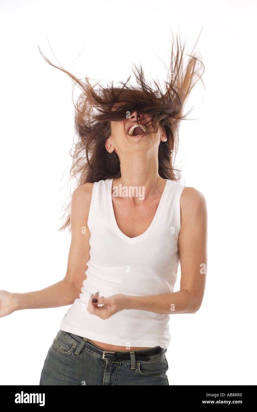 portrait of a young darkhaired woman in jeans and white top, laughing, with blowing hair Stock Photo