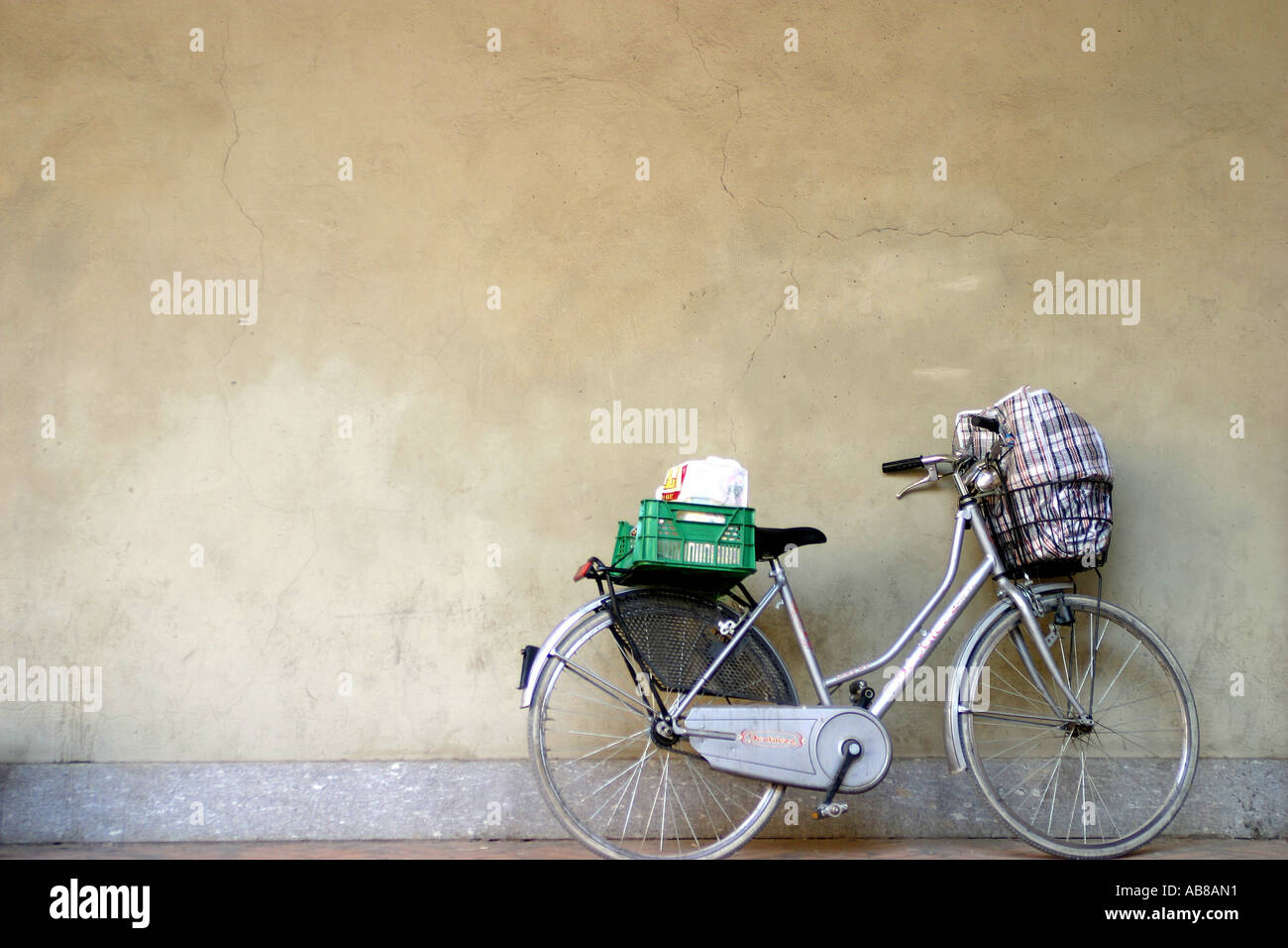 womans bicycle with shopping basket, leaning against a wall Stock Photo