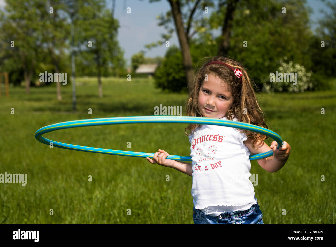 Young girl doing the hula hoop in the green Stock Photo