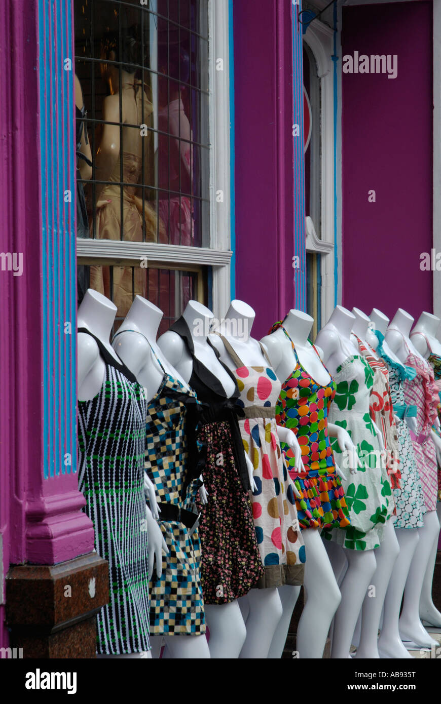 Row of white female mannequins in colourful summer dresses outside