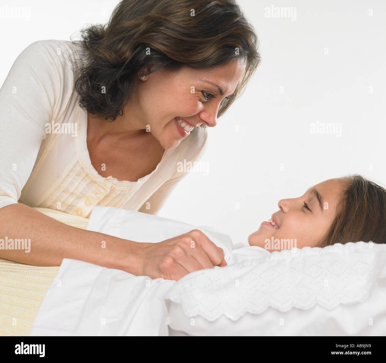 Mother tucking her daughter into bed Stock Photo Alamy