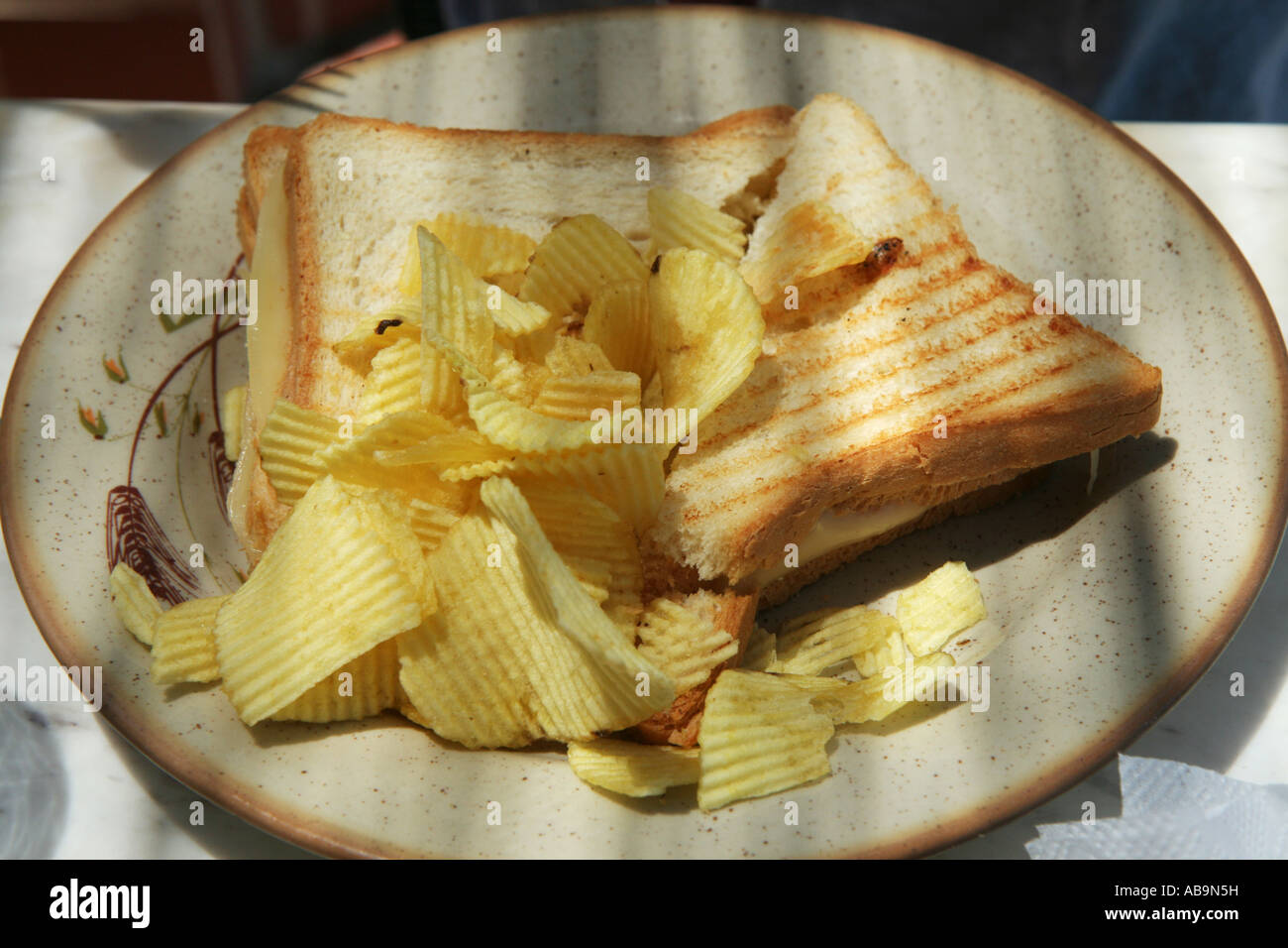 A plate with a ham and cheese double toast with chips crisps Stock
