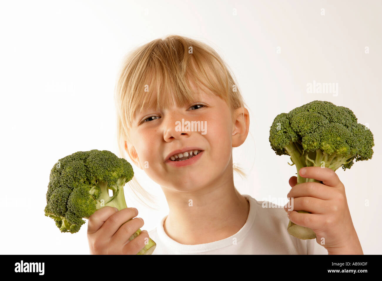Young girl holding broccoli showing an expression of dislike Stock