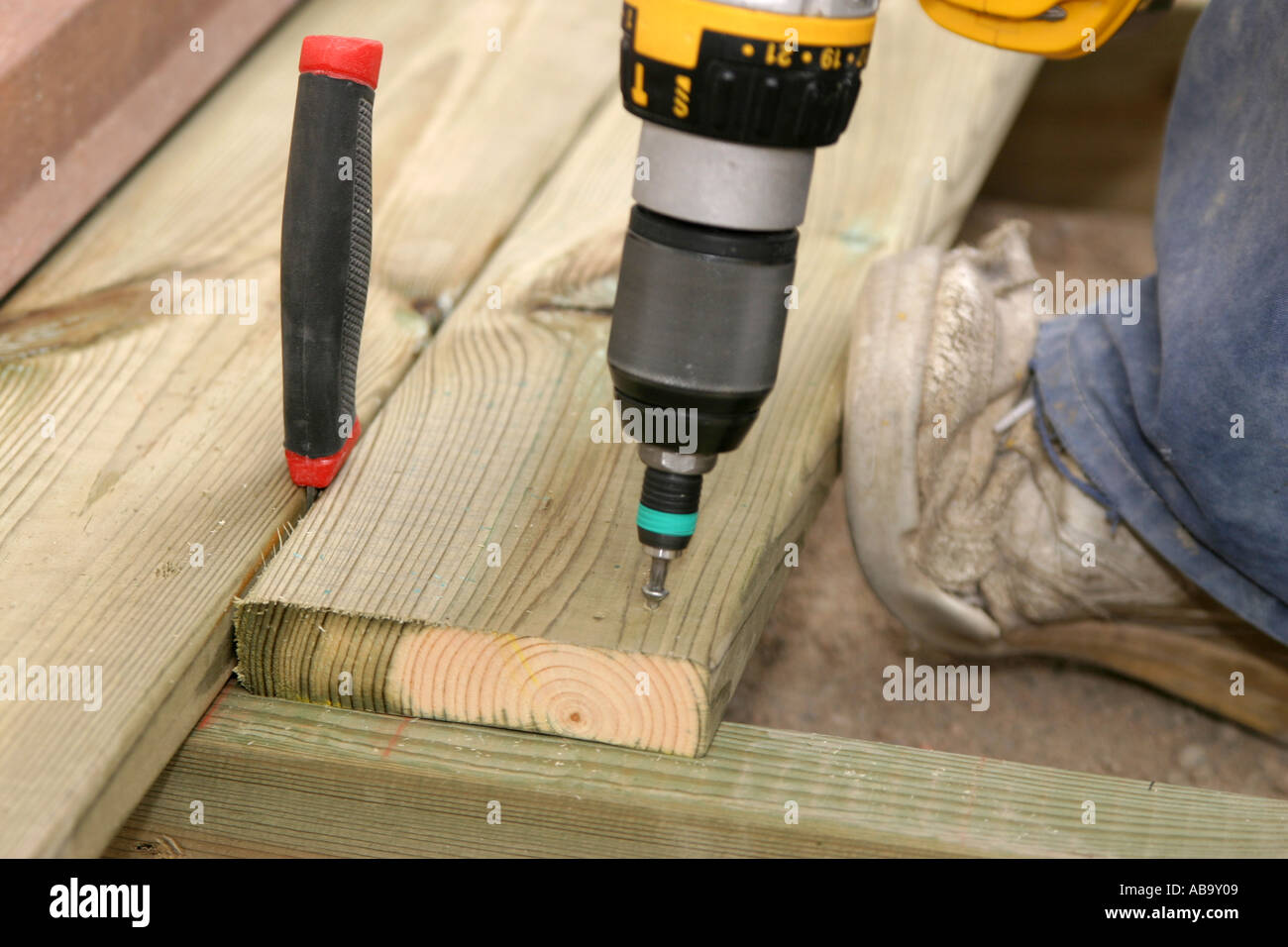 Fastening planks on a terrace with screws using a battery powered screwdriver Stock Photo