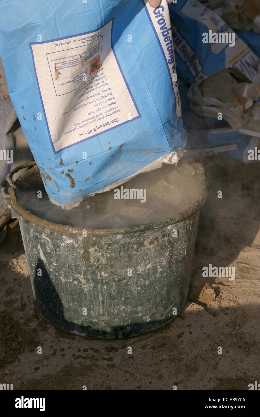 Pouring concrete powder into a bucket of water Stock Photo - Alamy