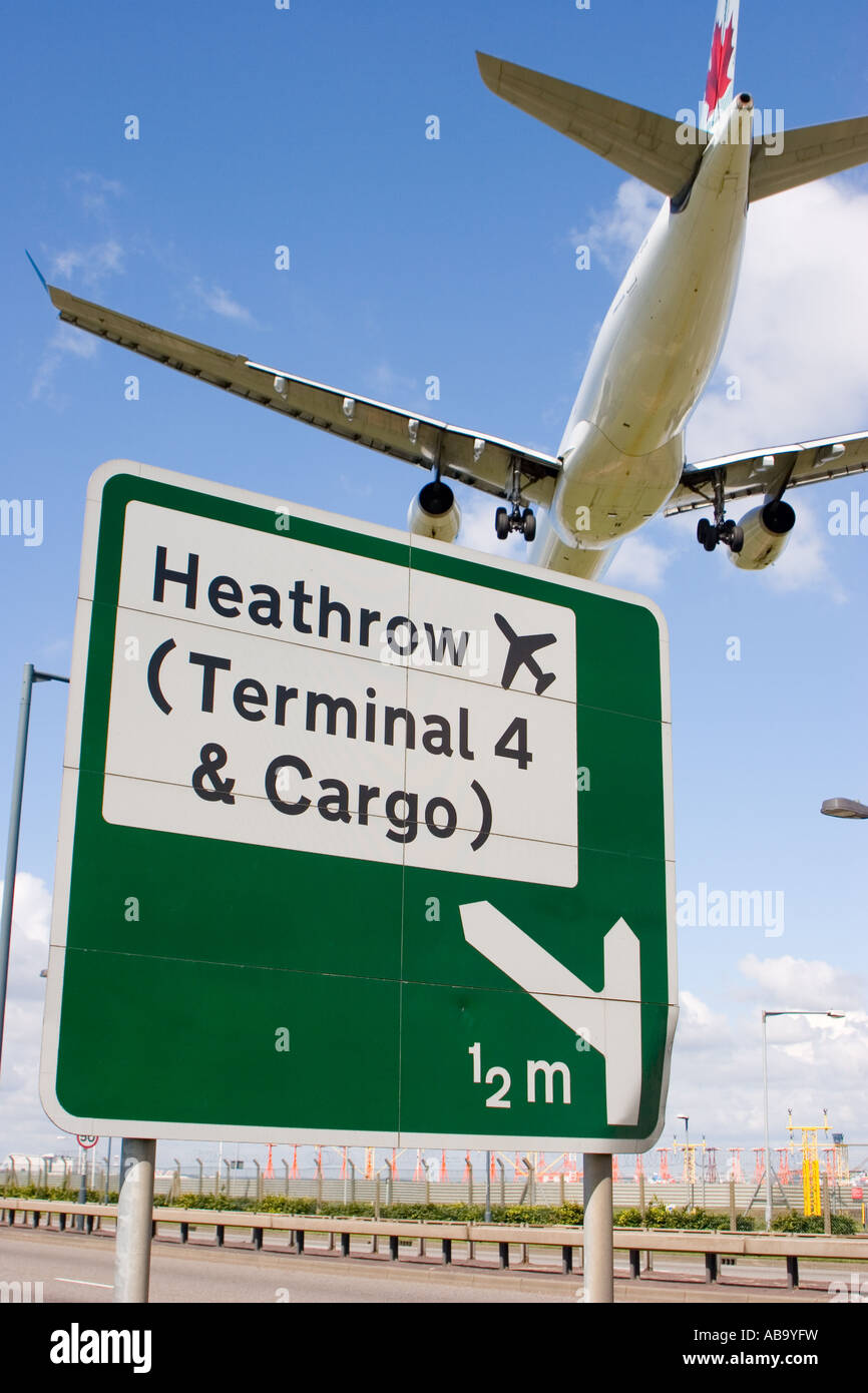 Road sign on the A4 for Heathrow airport with a low flying plane passing over head Stock Photo