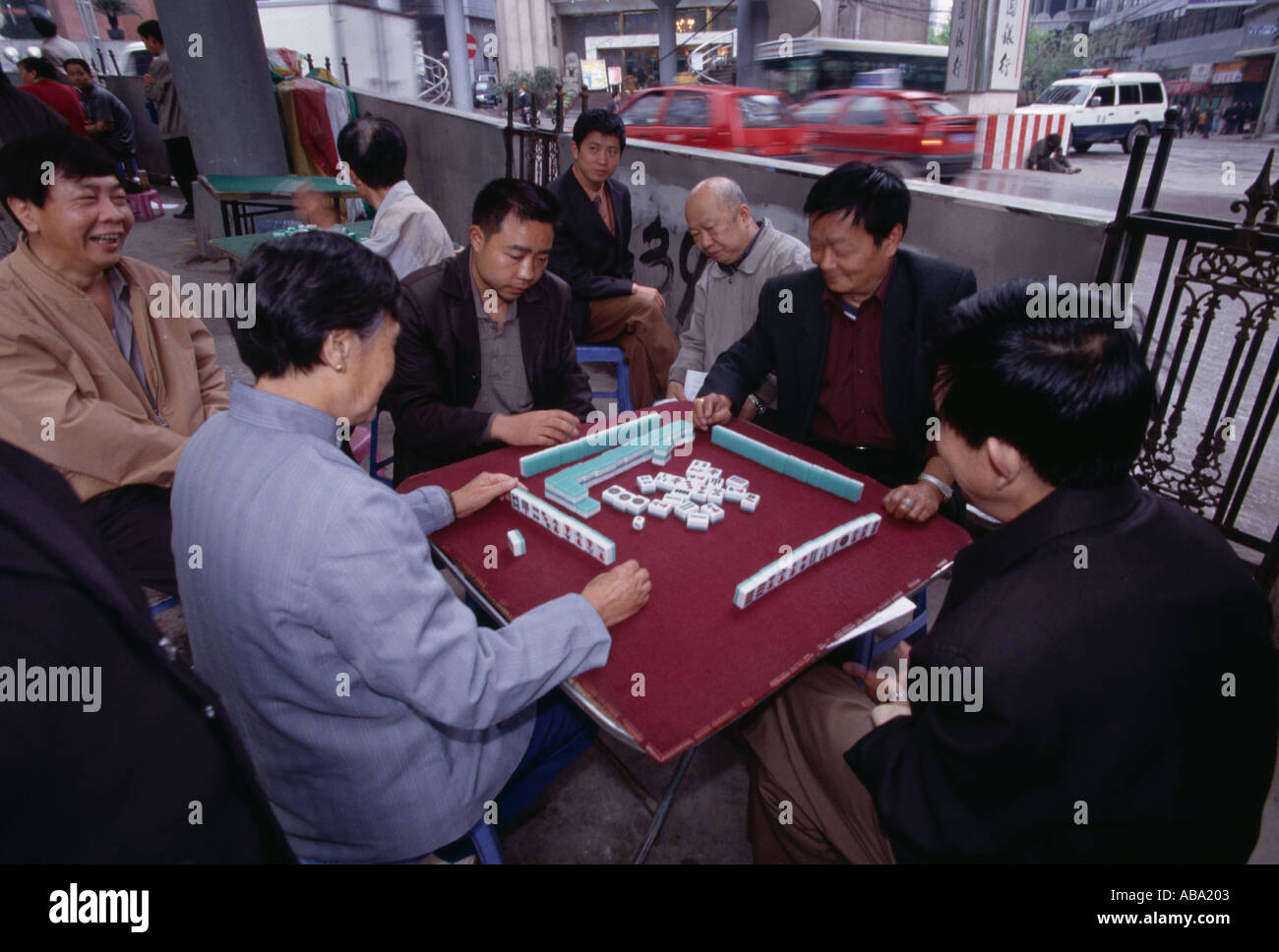 Men playing game of mahjong in outdoor park near busy street in Wanxian China city morning 042203 Stock Photo
