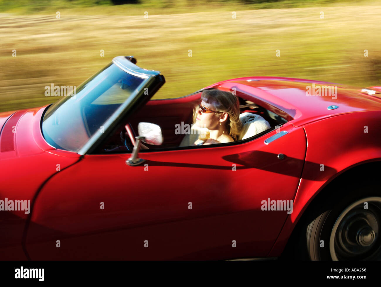 blond girl driving red convertible corvette Stock Photo