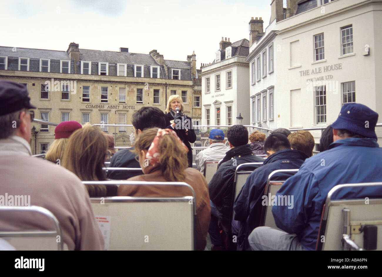 Open top double decker bus with passengers aboard taking city tour in Bath, UK, Abbey Hotel visible behind and The Ale House to right, Stock Photo