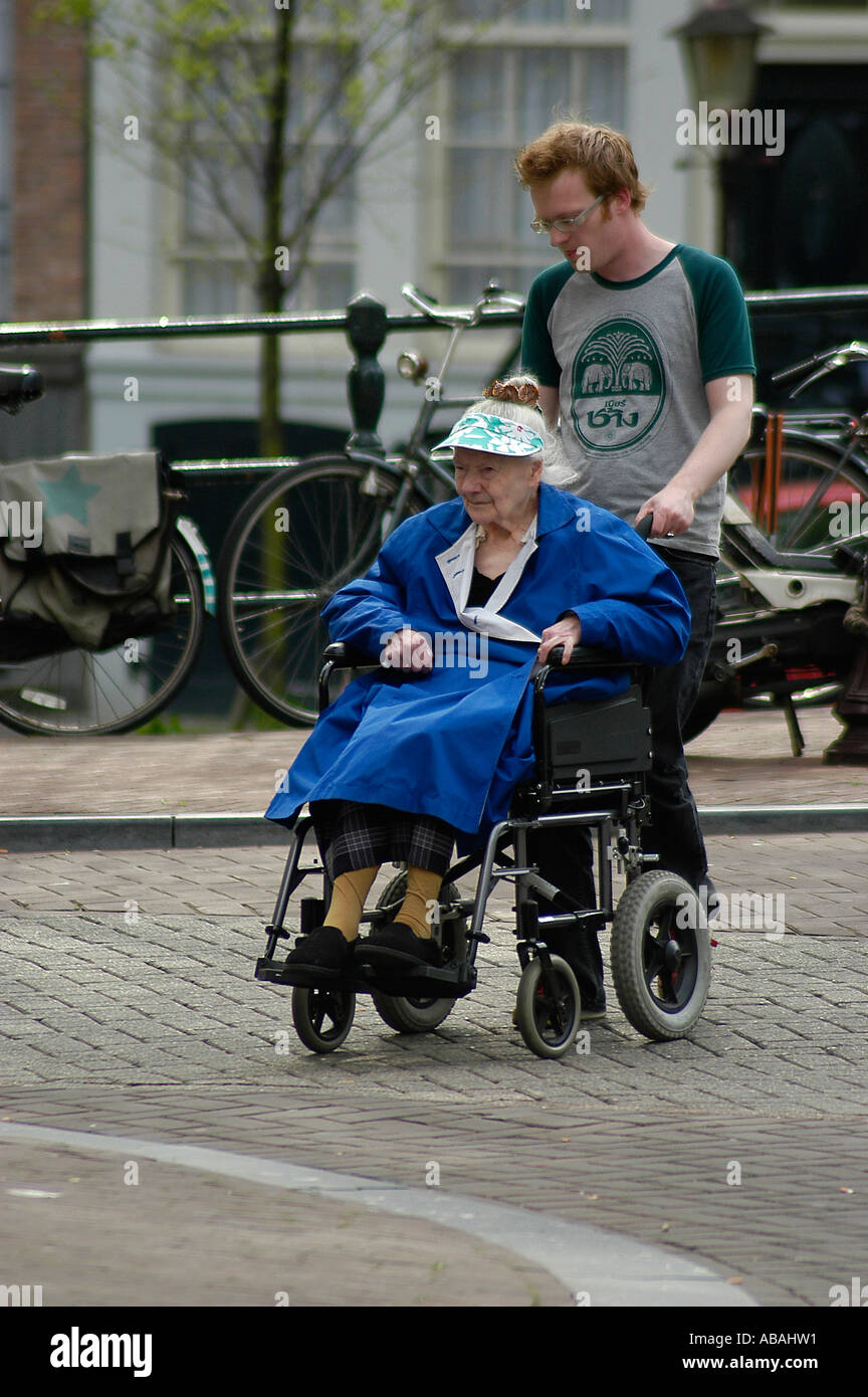 A young man helps a woman in a wheelchair crossing the street in Amsterdam  Stock Photo - Alamy