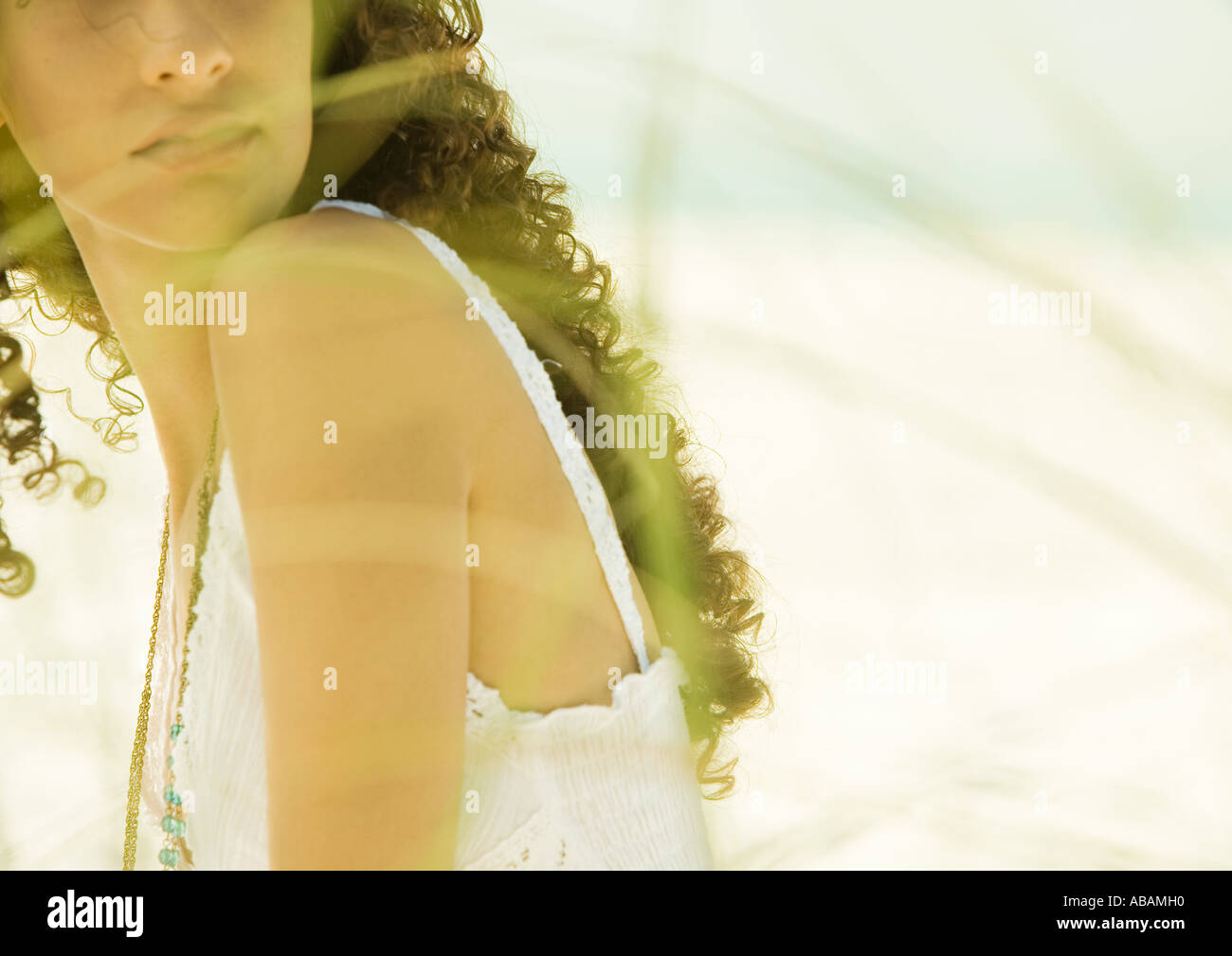 Woman with long curly hair, dune grass blurred in foreground Stock Photo