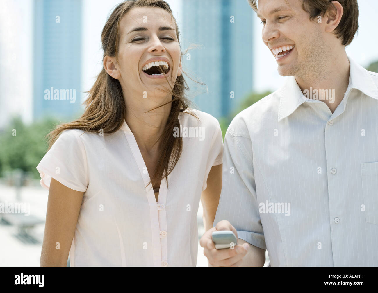 Young couple laughing as man holds cell phone Stock Photo