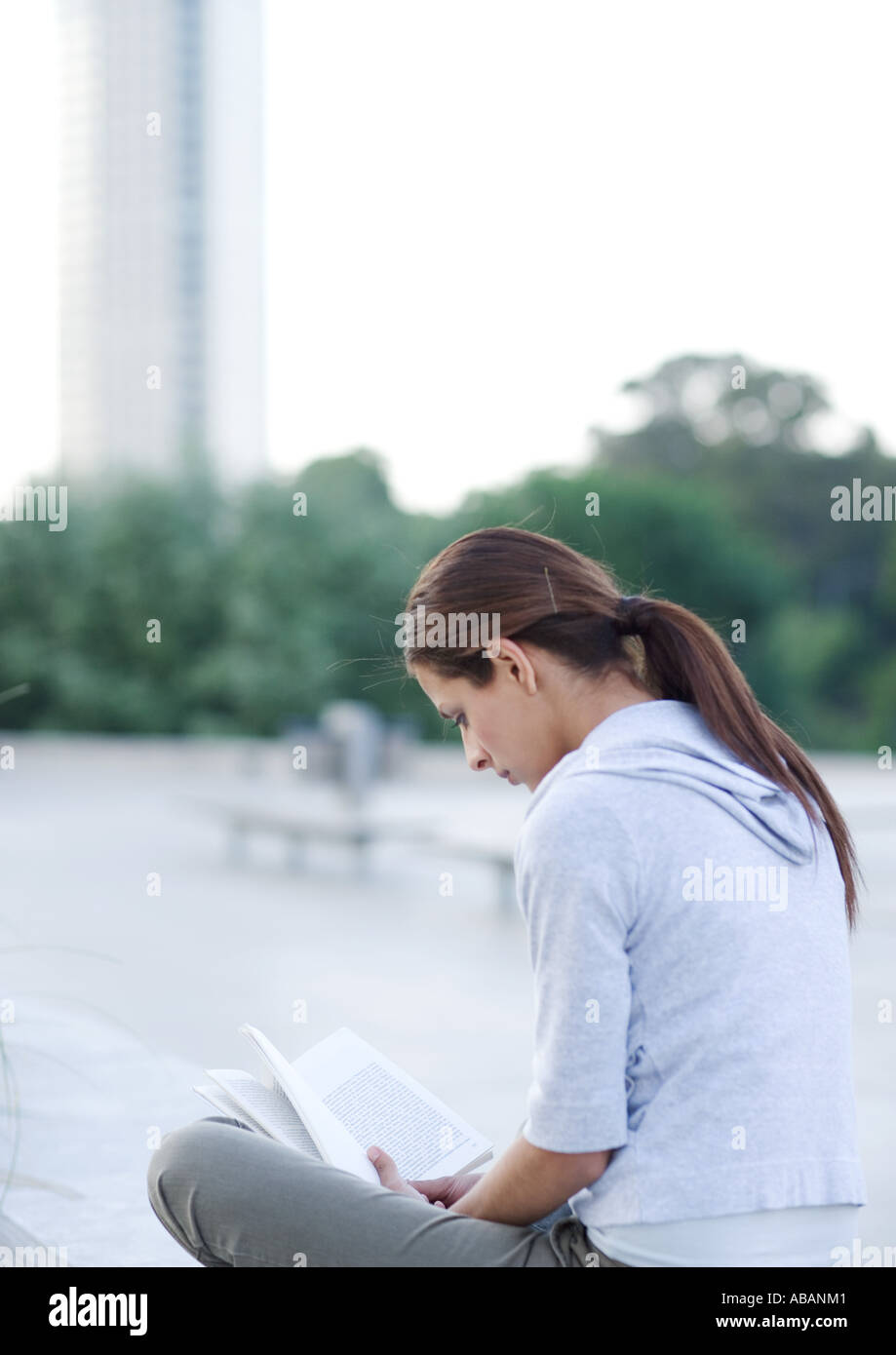 Young woman reading outdoors on college campus Stock Photo