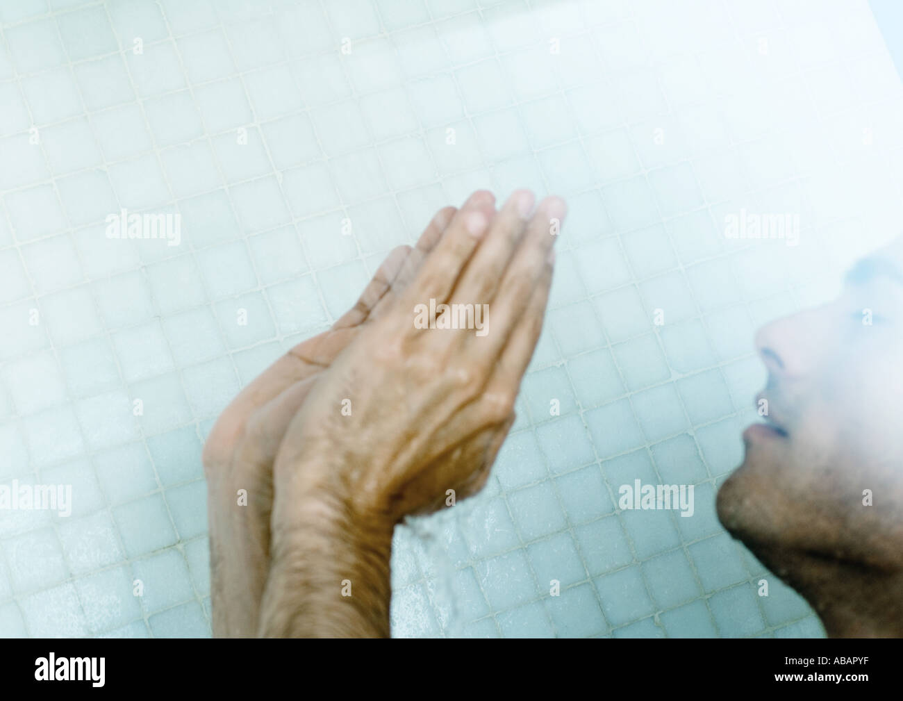 Man in shower with hands up Stock Photo