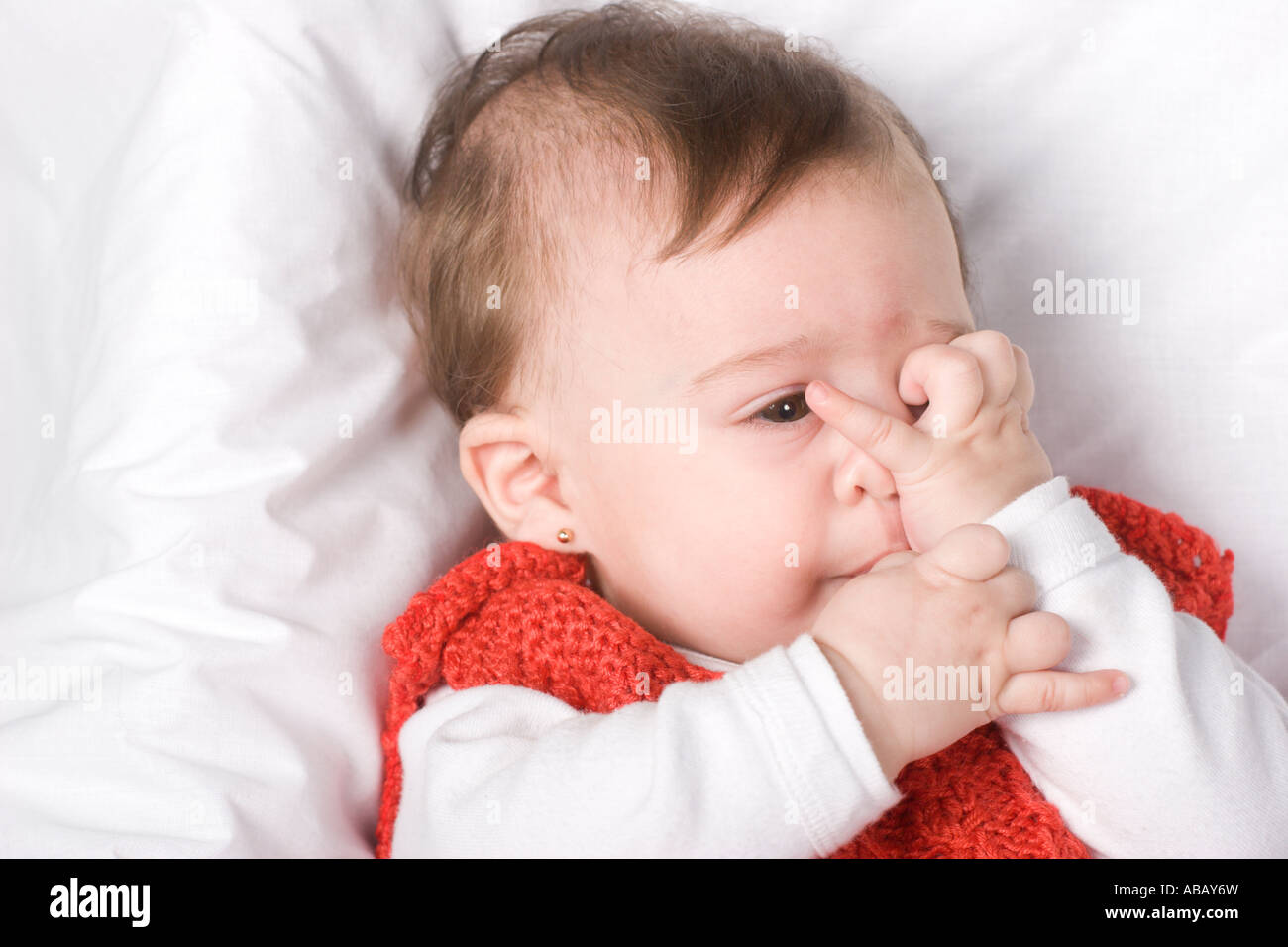 Baby girl covering her face with her hand as she would be embarrassed