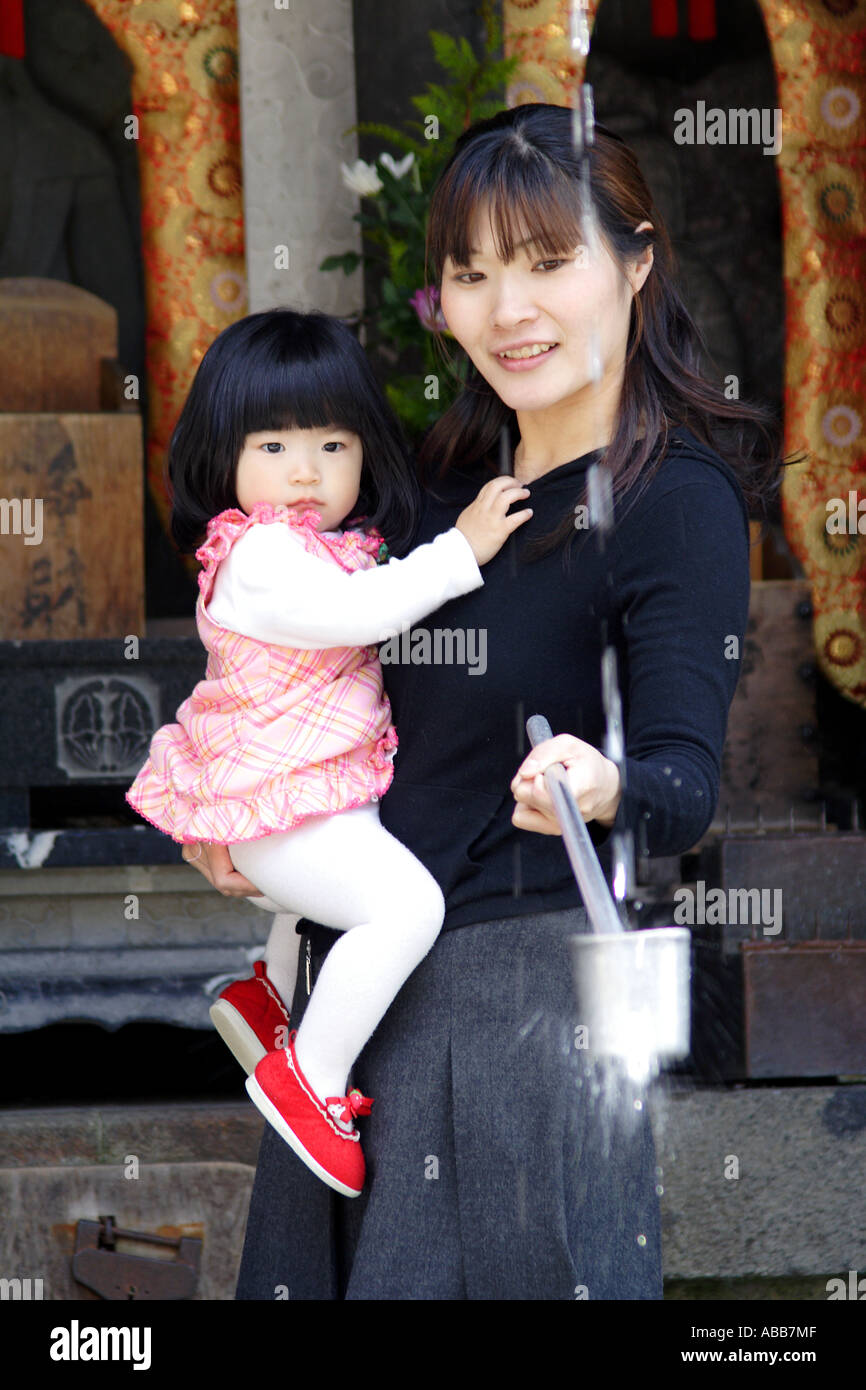 Mother and Daughter Drink from a Spring in The Kiyomizudera Temple Complex in Kyoto Japan Stock Photo