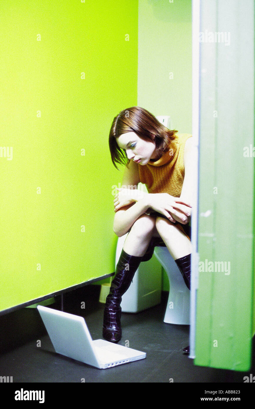 Woman sitting on lavatory with laptop computer Stock Photo