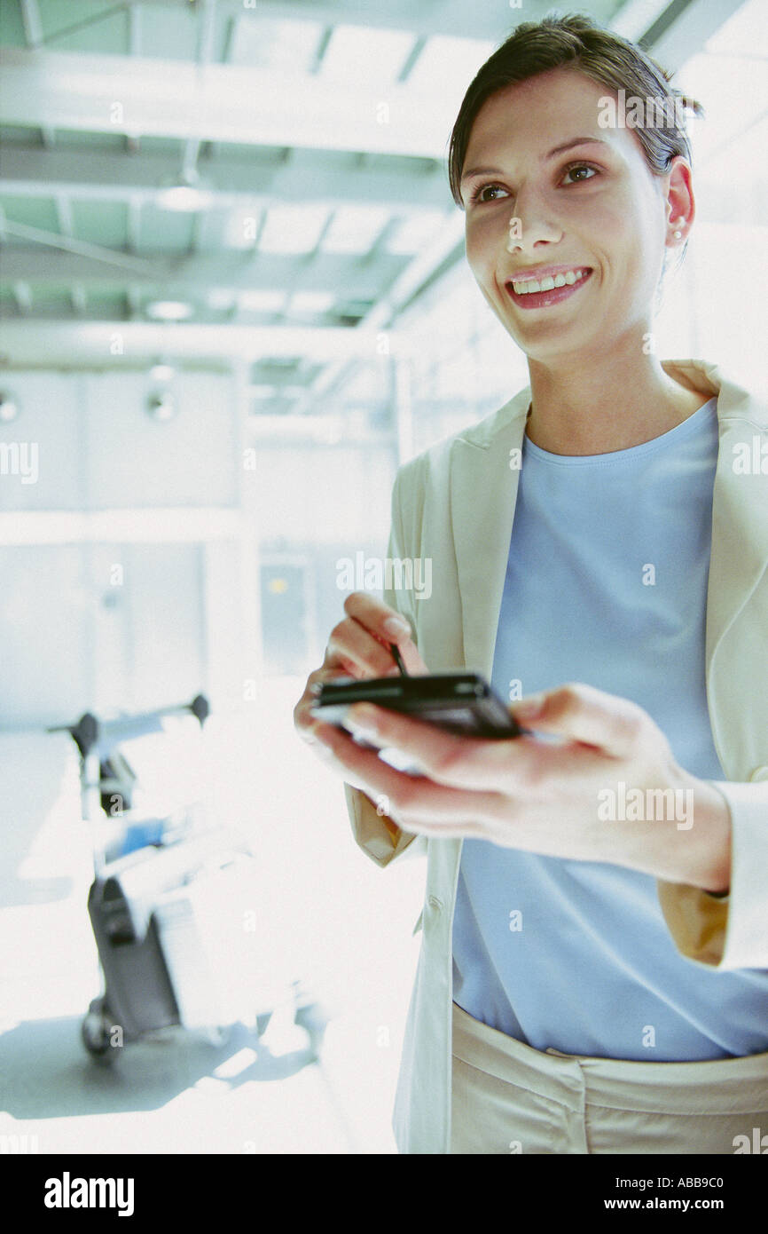 Businesswoman with palmtop at airport Stock Photo
