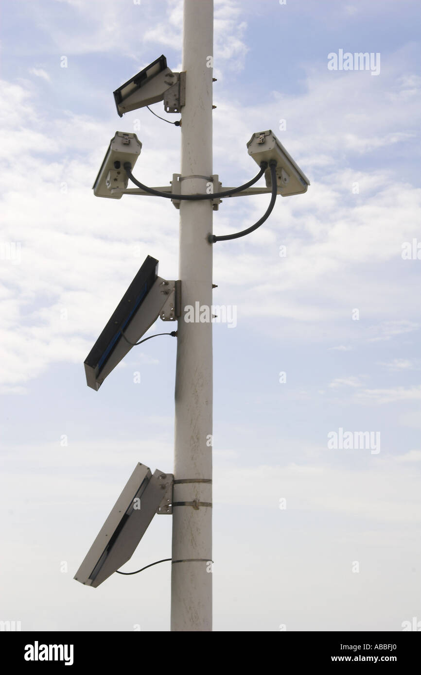 Multiple security cameras mounted on metal post and sky hi-res stock