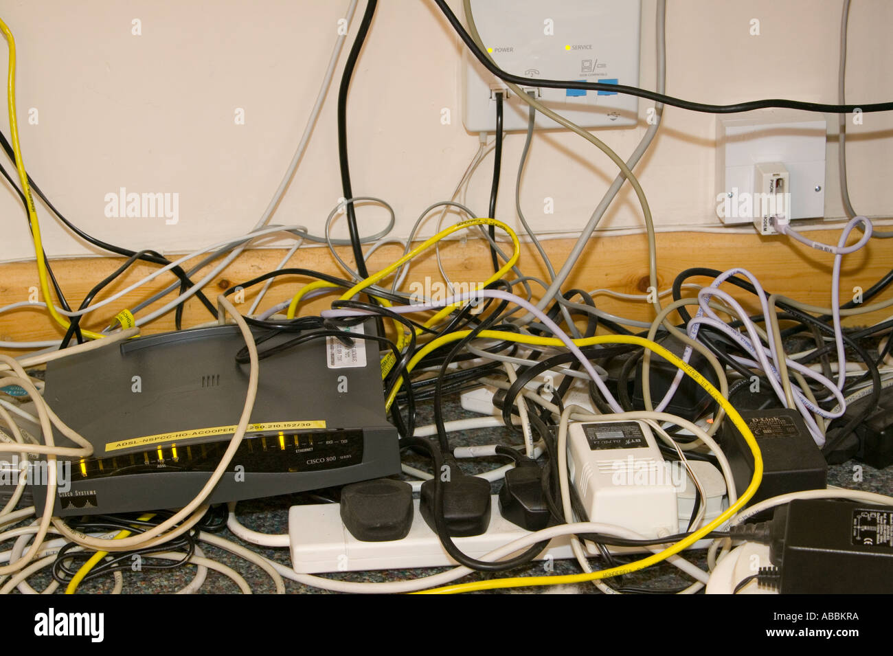 a tangle of computer wires underneath a desk in a workplace Stock Photo