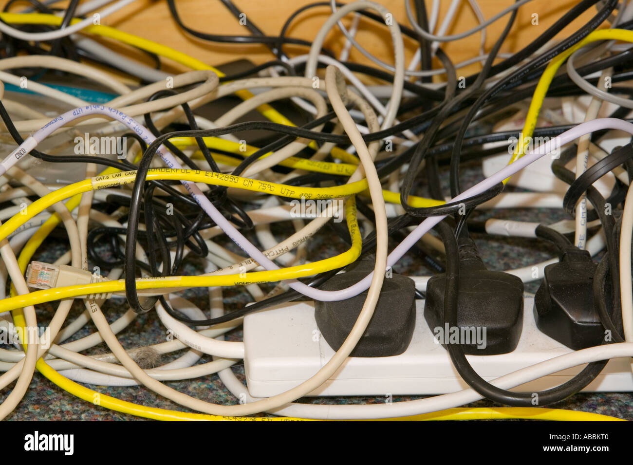 a tangle of computer wires underneath a desk in a workplace Stock Photo