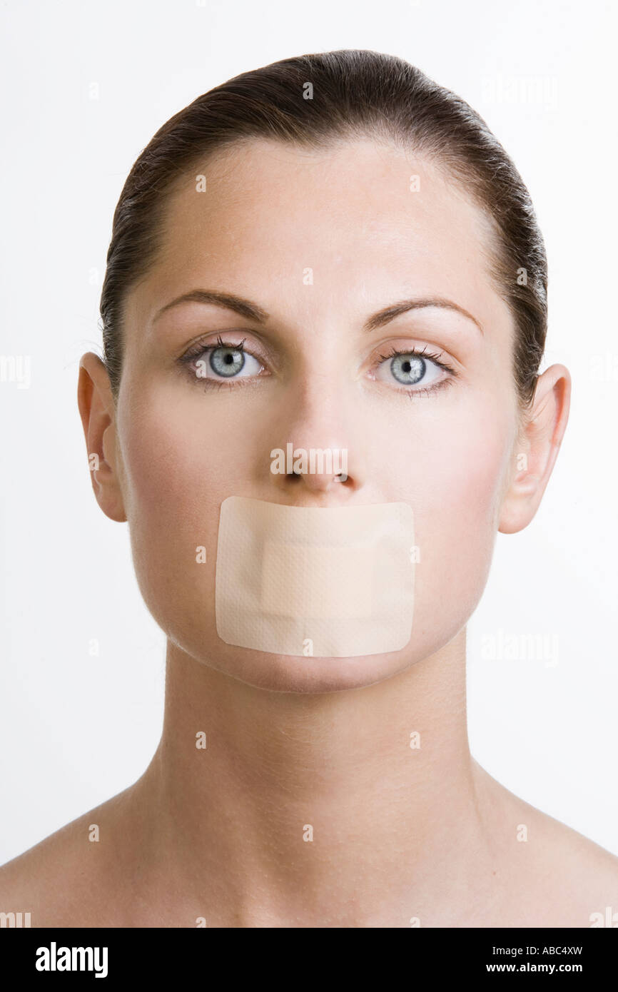 headshot of young woman with plaster over mouth looking at camera Stock