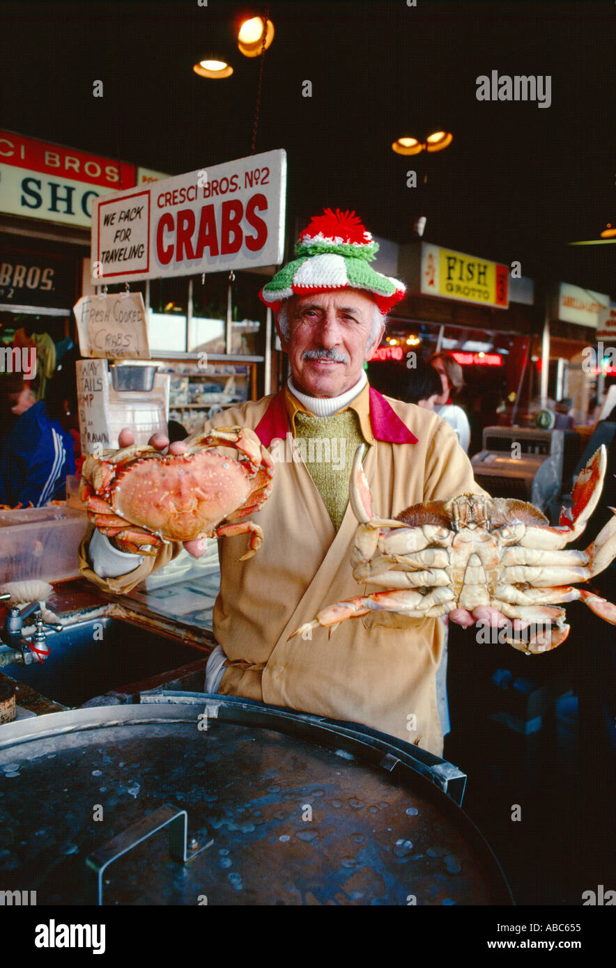 Fisherman's Wharf merchant holding up and presenting cooked crabs in