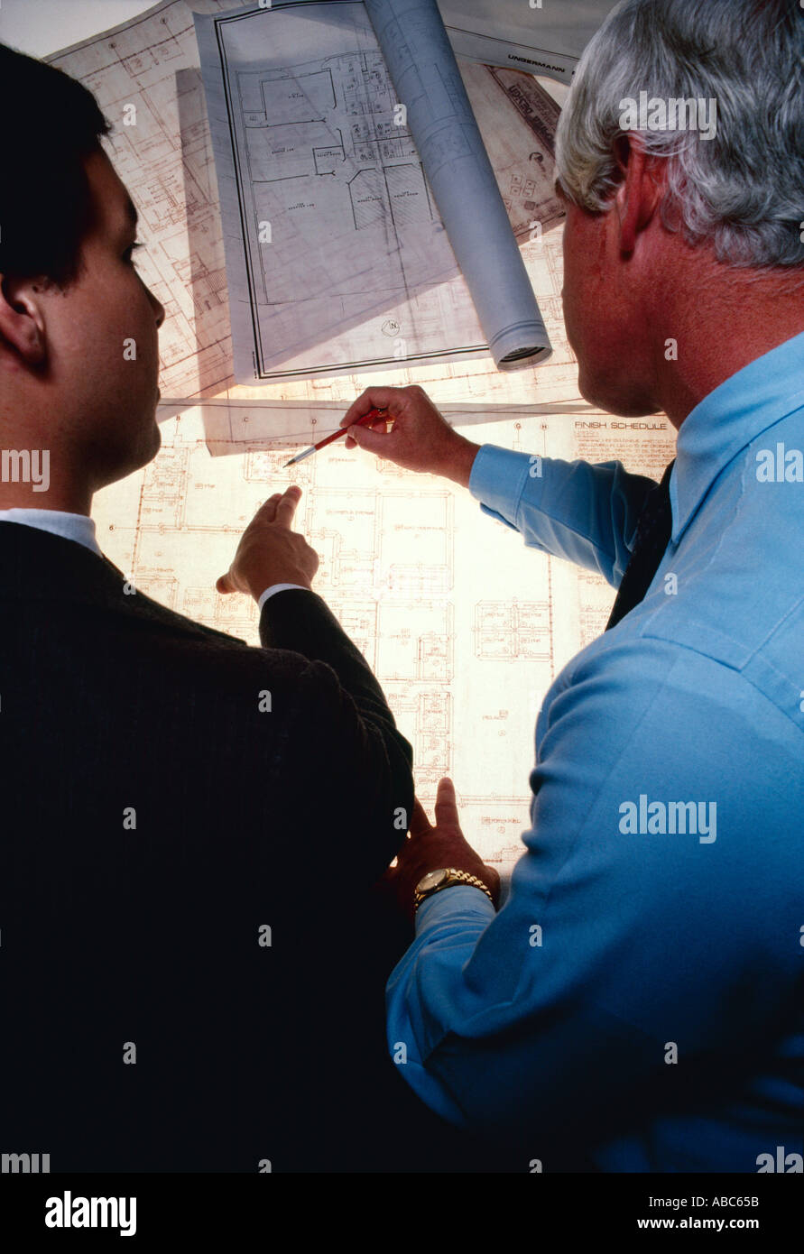 Architecture / Business - Architects, businessmen, executives inspecting, reviewing, examining blueprints on a light table. Stock Photo