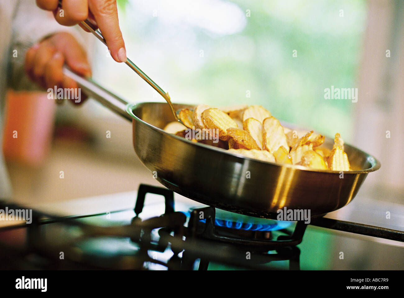 Sliced fried potatoes in a pan on a gas oven Stock Photo