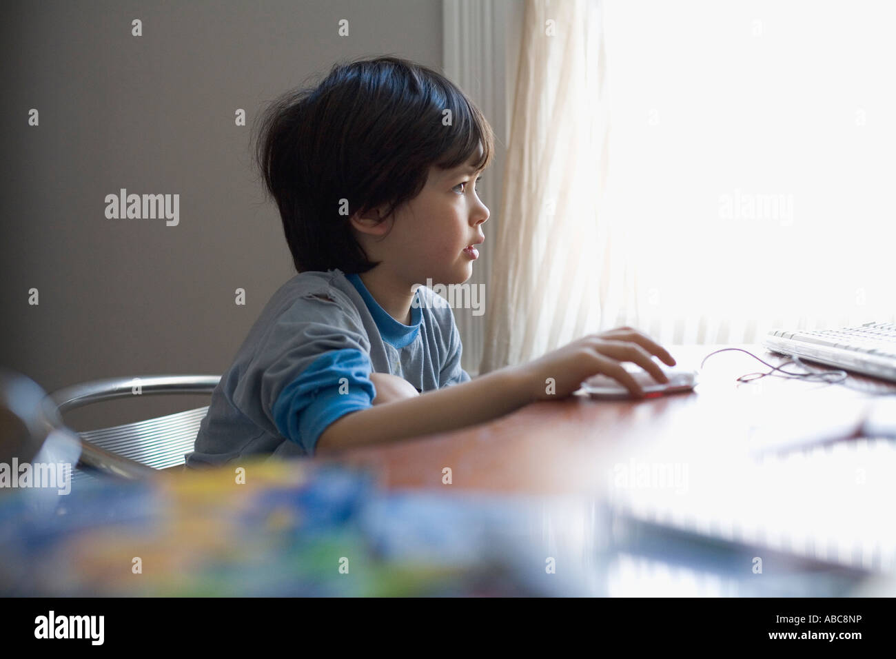Young Boy in pajamas playing computer game at home. Model Released Stock Photo