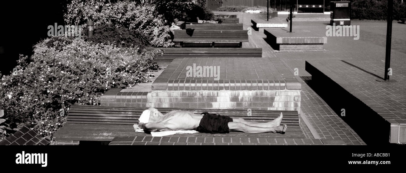 Man sunbathing on a bench in the City of London Stock Photo