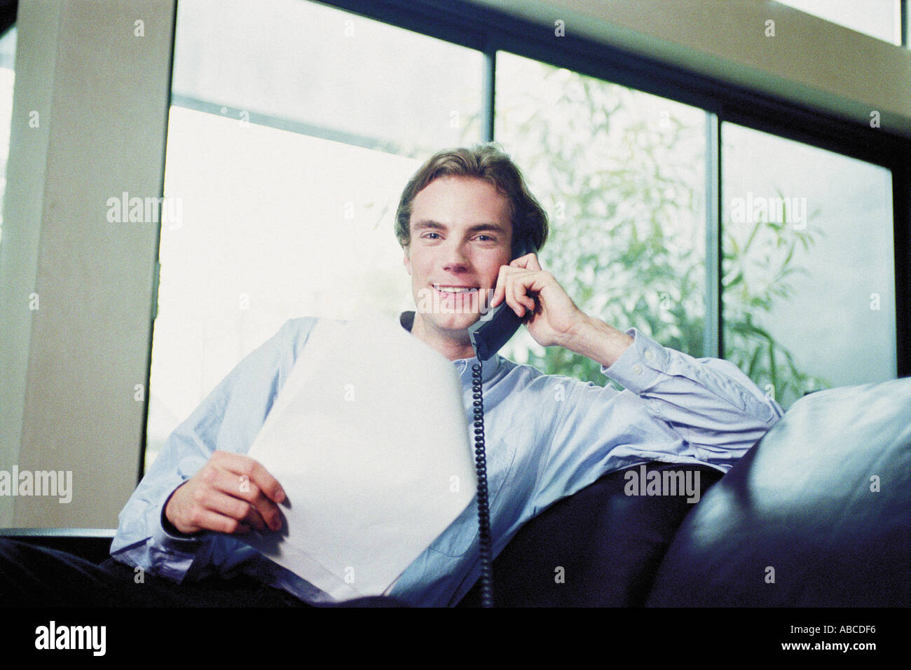 Man sitting on sofa with telephone Stock Photo