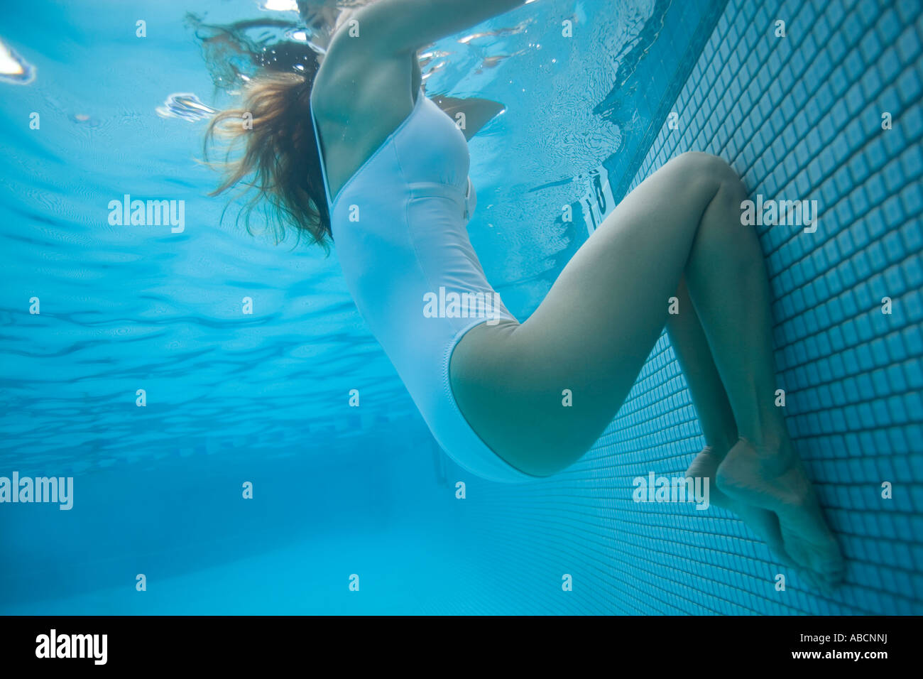 Underwater view of adult female resting at edge of swimming pool Stock Photo