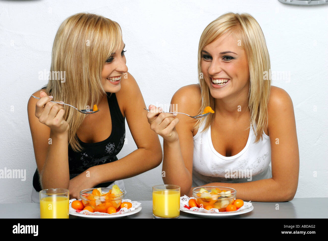 Blond twins eating fruit salad Stock Photo