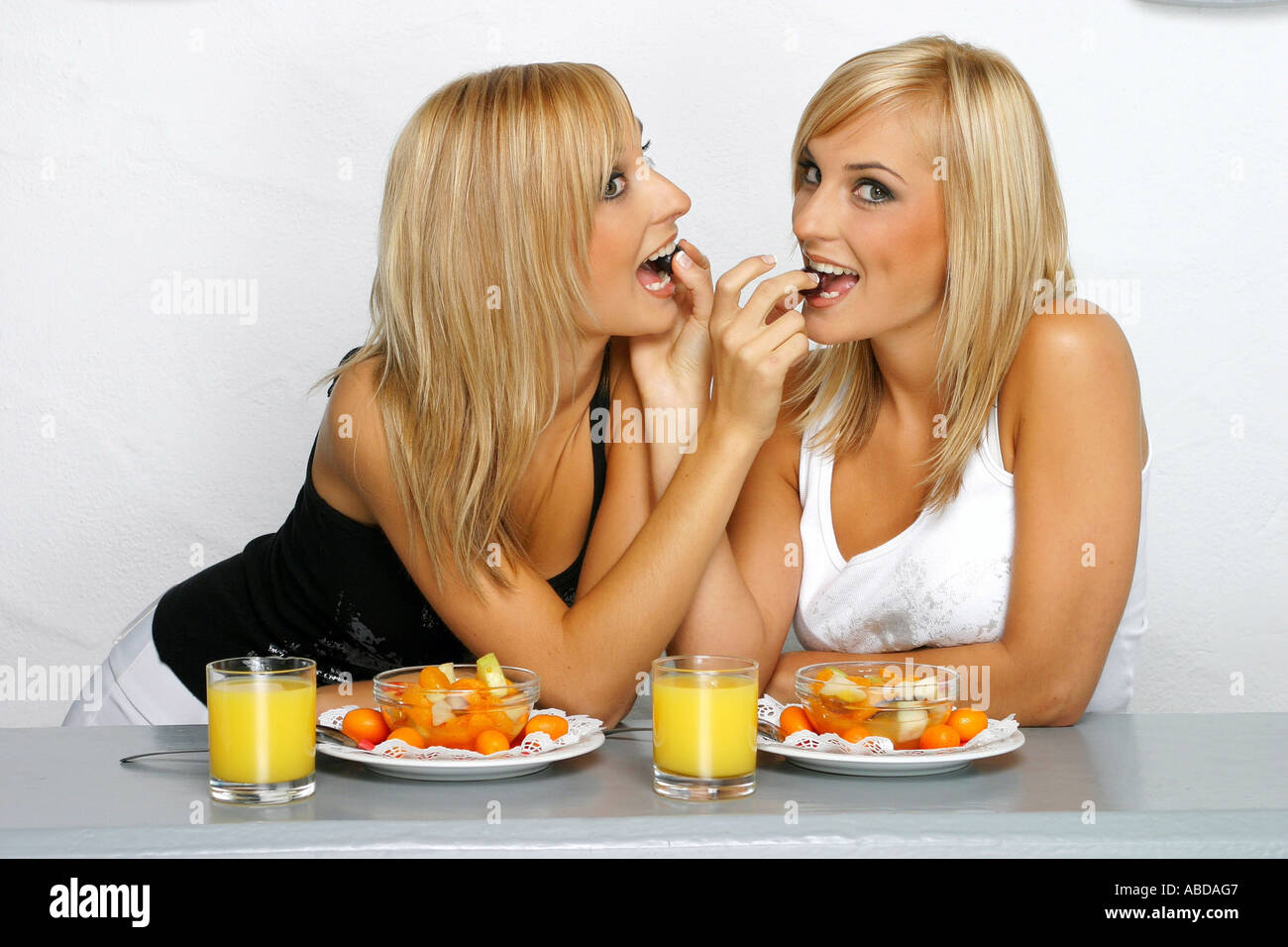 Blond twins feed themselves with fruit salad Stock Photo