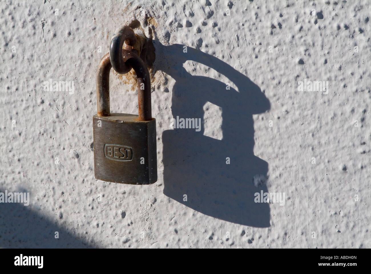 Padlock hanging on metal eyehook on wall Stock Photo
