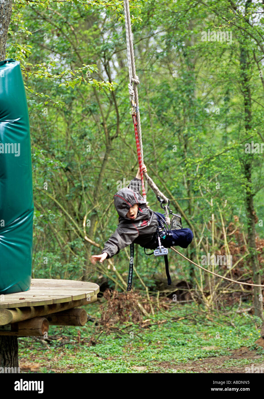 Boy swinging on a rope reaching the platform Stock Photo