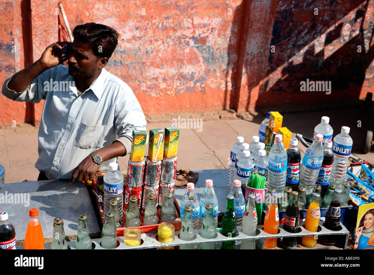 India, Agra salesman with soft drinks and mobile phone contrasts Stock