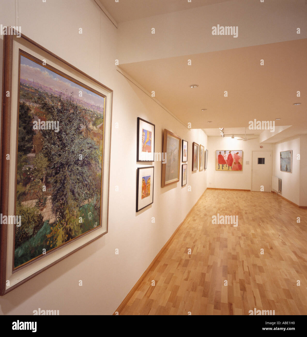 Collection of paintings on walls of modern art gallery with wooden flooring Stock Photo Alamy
