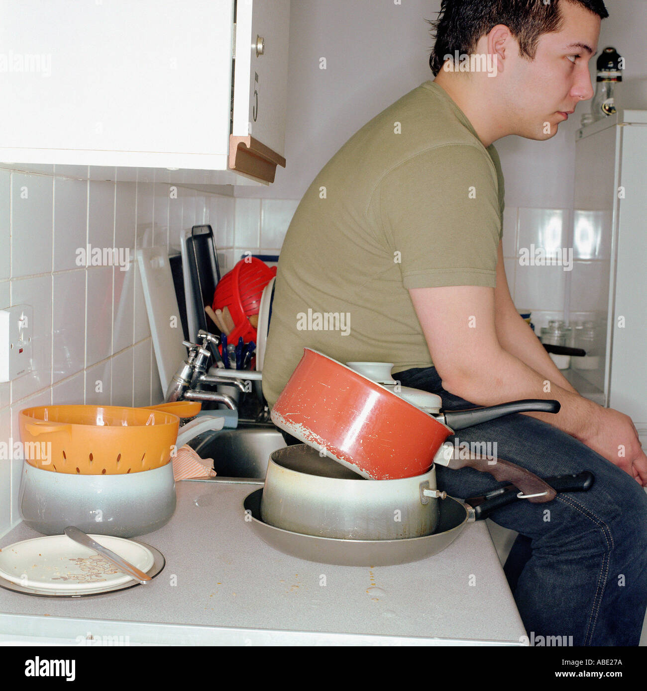 Boy sitting in a messy kitchen Stock Photo